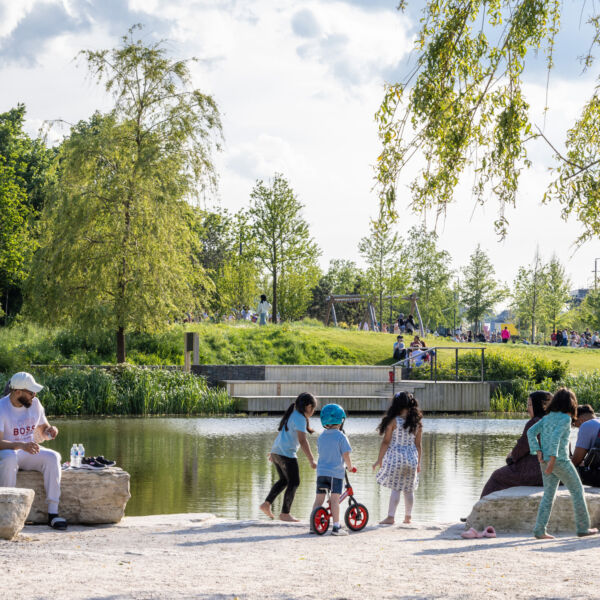 A family sitting beside the lake in Claremont Park, Brent Cross Town