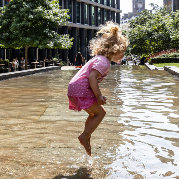Young girl enjoying the water during hot weather in Pancras Square, King's Cross